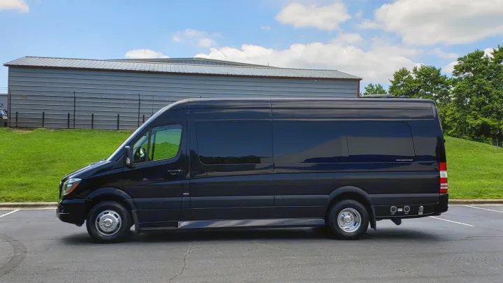 A sleek black Mercedes-Benz Sprinter luxury van, an ideal RV rental, parked on asphalt with green grass.. Mercedes-Benz Sprinter 2015