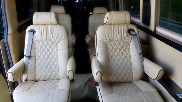 Plush, cream leather captain's chairs inside a luxurious RV rental, offering comfortable seating with diamond quilting.. Mercedes-Benz Sprinter 2015