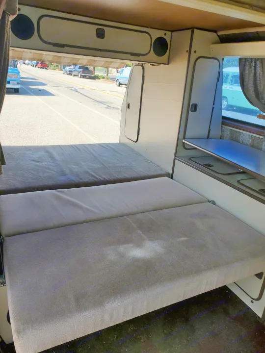RV rental: Camper van interior features convertible beds & storage, offering a clear road view.. Volkswagen Westfalia 1982
