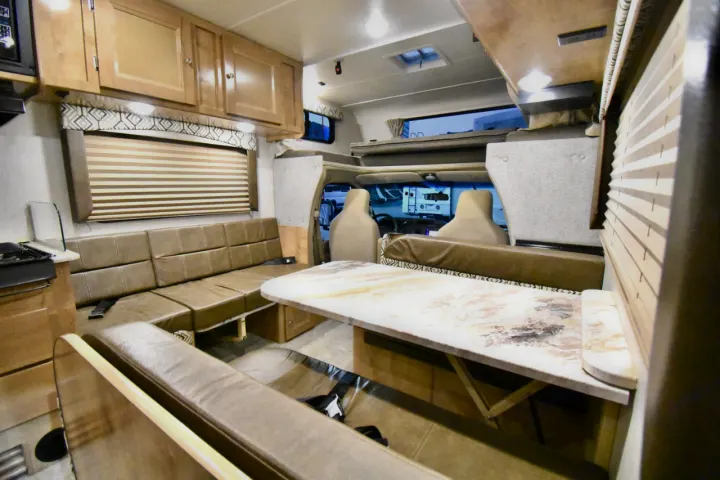 Spacious rv rental interior features a dining booth, sofa, and over-cab bunk for comfortable living.. Leprechaun 230RB 2020