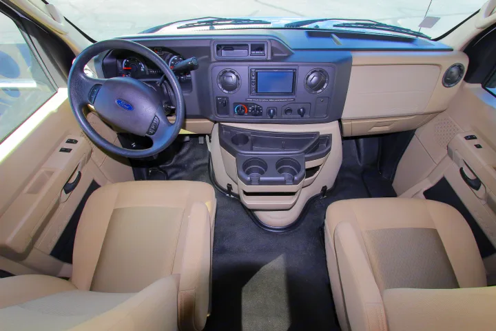 Ford RV rental cabin interior: dashboard, steering wheel, front seats, and central console with cup holders.. Leprechaun 230RB 2020