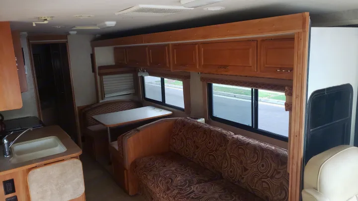 RV rental interior: kitchen, dining booth, sofa, and overhead cabinets provide a comfortable space.. Winnebago Sightseer 2007