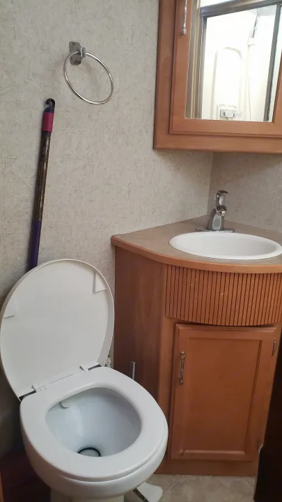 Compact RV rental bathroom with toilet, corner sink, and mirror reflecting the shower area.. Winnebago Sightseer 2007