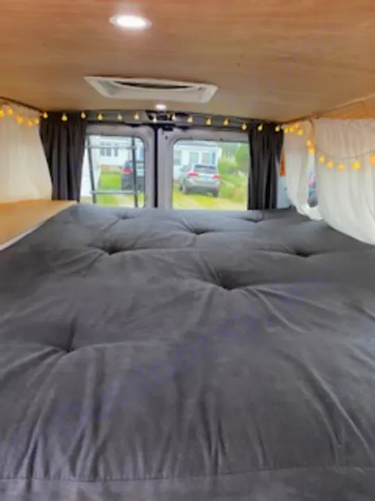 Experience a comfortable RV rental! This custom van interior features a plush grey tufted bed, wood walls, and cozy lights.. Ford Econoline E250supercab 1999