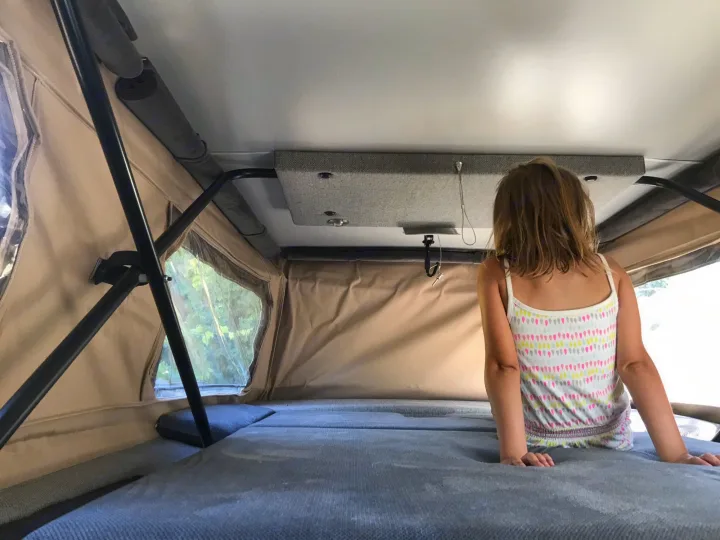 Inside an RV rental: a young girl enjoys the cozy sleeping area, perfect for travel adventures and camping.. Mercedes Sprinter 2018