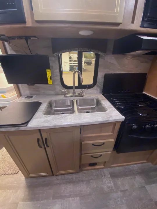 This RV rental's kitchen features a double sink, gas range, countertop, and mounted TV. Compact and ready for adventure.. Winnebago Micro Minnie 2021
