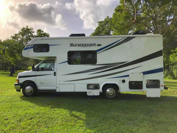This white Sunseeker RV rental is parked on green grass under a cloudy sky, ready for an outdoor adventure.. Forest River sunseeker LE 2350 2020
