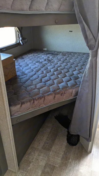RV rental bedroom: A comfy gray quilted mattress and wood-look flooring inside a compact sleeping space.. Forest River Rockwood Mini Lite 2020