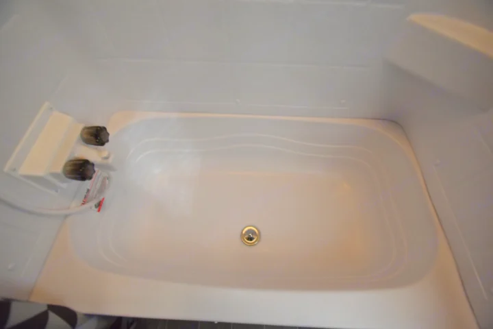 White, clean RV rental shower/bathtub unit with simple faucet controls and a visible drain.. Other Other 2020
