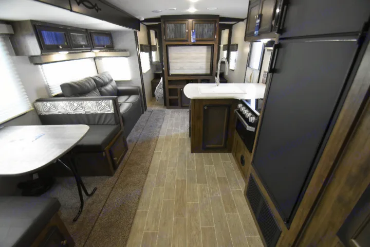Bright RV rental interior: cozy living area with sofa, dining booth, and fully equipped kitchen with stove, sink, and fridge.. Other Other 2020