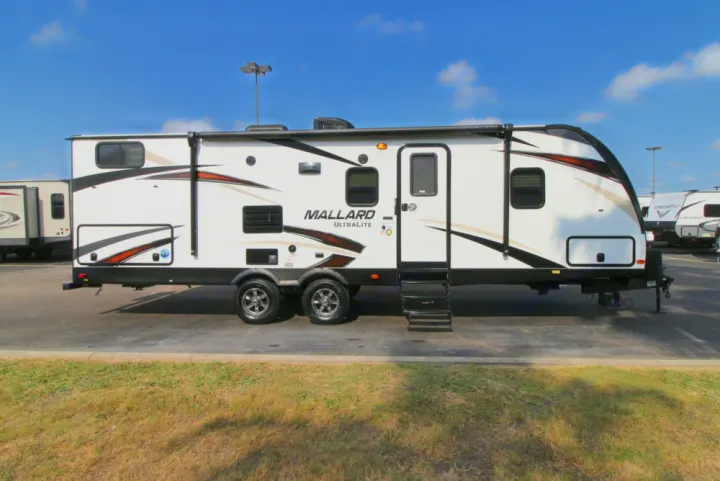 A white Mallard Ultralite travel trailer, ideal for your next RV rental adventure, parked on asphalt under a blue sky.. Other Other 2020