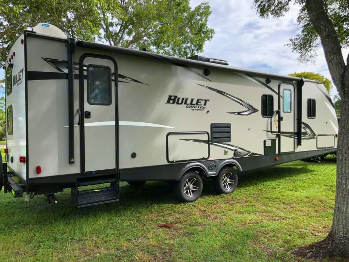 Bullet Ultra Lite travel trailer for RV rental, parked on green grass, ready for your next adventure.. Keystone Bullet 2020