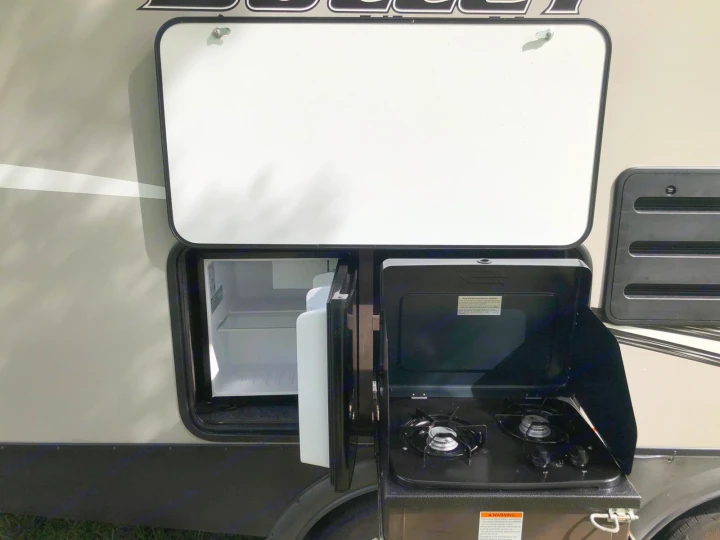 RV rental: Discover the side hatch revealing a compact outdoor kitchen with a mini-fridge and two-burner camp stove for travel.. Keystone Bullet 2020