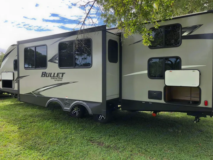 Tan Bullet Ultra Lite travel trailer with an extended slide-out and open storage, ready for your rv rental.. Keystone Bullet 2020