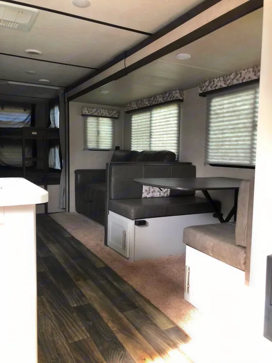 This RV rental's spacious interior features a functional living area with bunk beds, sofa, and a dinette booth.. Keystone Bullet 2020