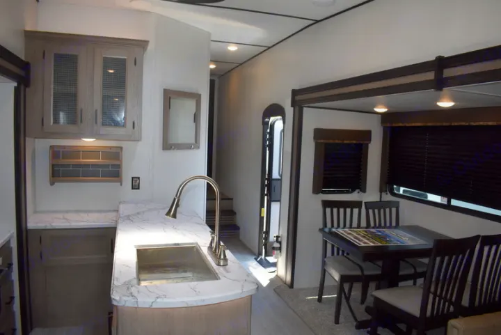 Inside a clean RV rental: kitchen with marble-look counters, dining table, and a hallway leading to the back.. Other Hideout 2021