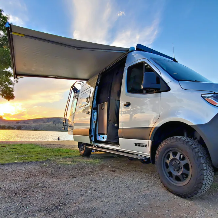 This Winnebago rv rental offers stunning lake sunset views, with its awning extended for comfy outdoor living.. Winnebago Revel 2020
