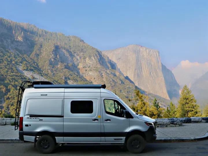 Silver Winnebago Revel camper van on a mountain overlook, with towering peaks in the background. Great for an rv rental trip!. Winnebago Revel 2020