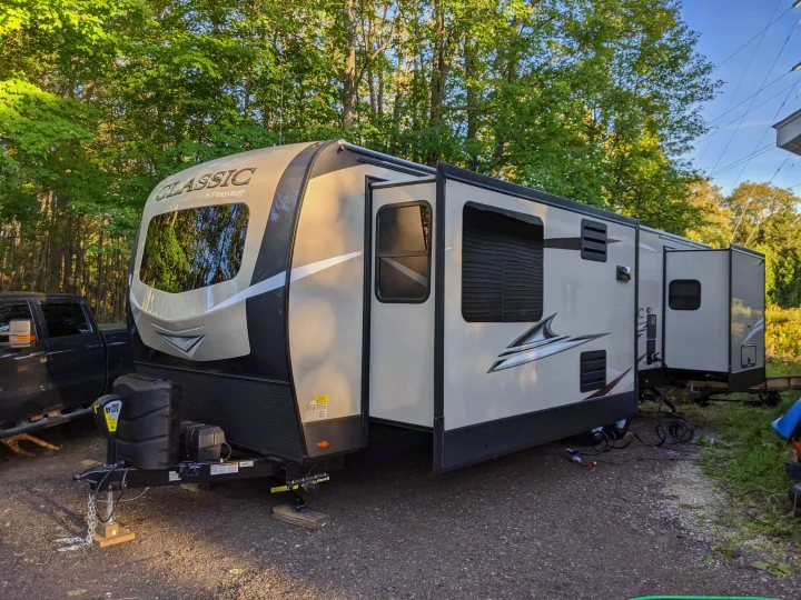 A spacious Flagstaff Classic travel trailer, ideal for an RV rental getaway, parked among tall trees in a natural setting.. Forest River Forest River Flagstaff Classic Super Lite 2021