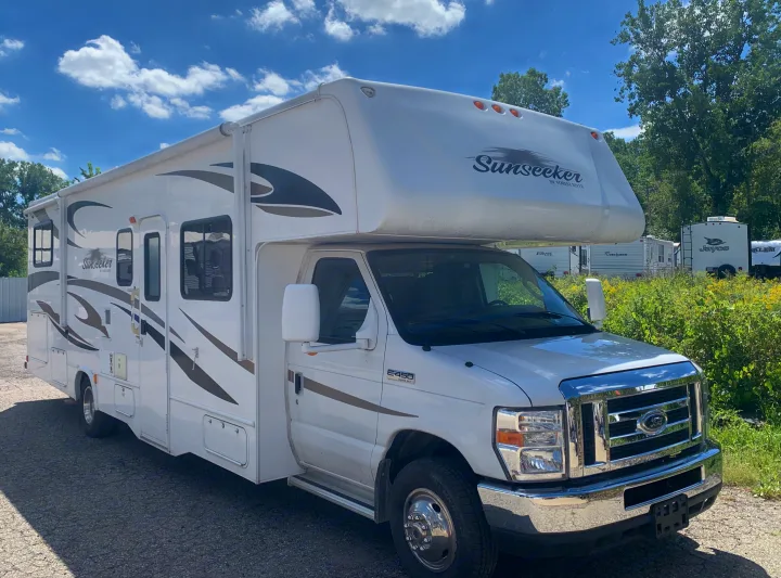 A bright white Sunseeker RV rental motorhome, built on a Ford E-450 chassis, is parked outdoors on a sunny day.. Forest River Sunseeker 2012