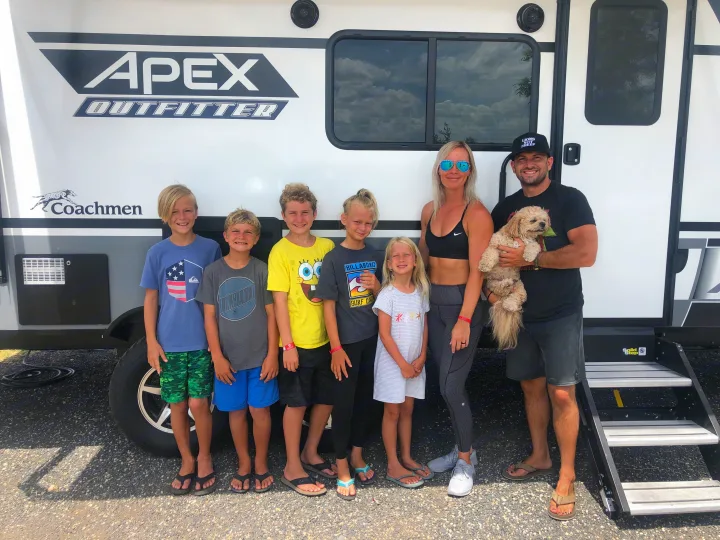 Smiling family and their dog by a white Coachmen. Coachmen Apex 2021