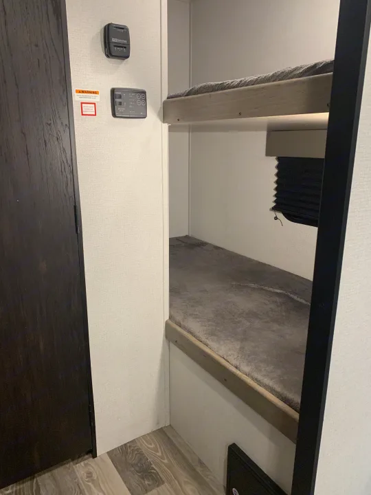 Inside an RV rental: cozy bunk beds, climate controls, and a door. Perfect for family adventures.. Keystone Hideout 2021