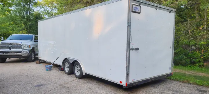 A white cargo trailer and silver pickup truck are parked on asphalt. Great for gear hauling on your next RV rental trip.. Team spirit Enclosed 24-foot 2019
