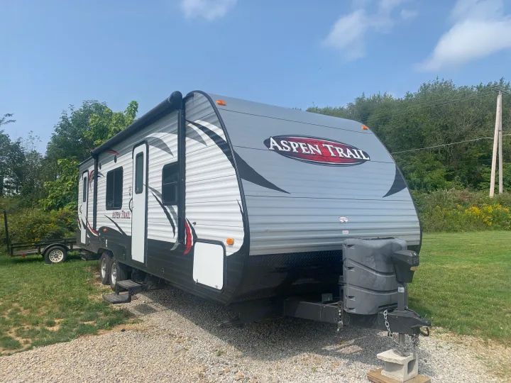 A gray Aspen Trail travel trailer (RV) parked outdoors, ready for your next rv rental adventure.. Dutchmen Aspen Trail 2014