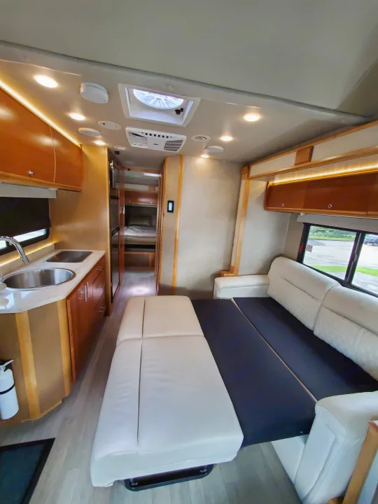 RV rental interior showcasing a bright kitchen, extended sofa bed, and rear bunk beds.. Wayfarer Wayfarer Motorhome 2017