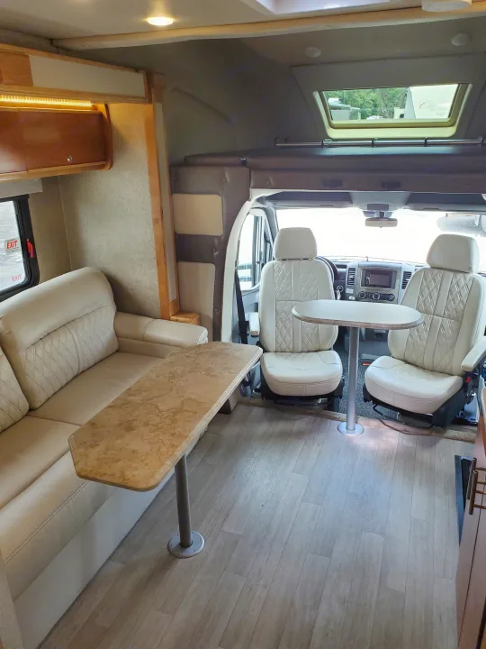 Spacious RV rental interior with light leather seating, tables, and front cabin. Ready for your next adventure!. Wayfarer Wayfarer Motorhome 2017