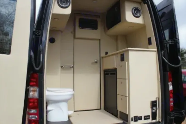 An RV rental's compact interior features a toilet and mini-fridge, showcasing efficient mobile living space.. Other Other 2020