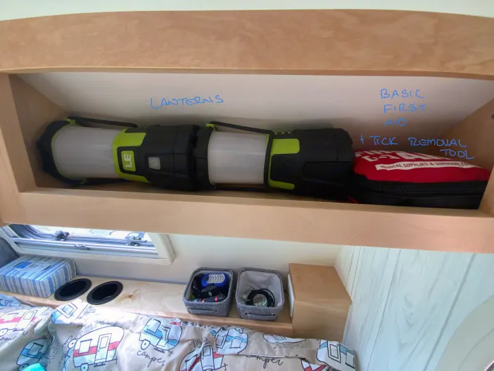 Organized RV rental interior: Lanterns and a first aid kit are neatly stowed on a shelf above the bed.. nuCamp T@G 2019