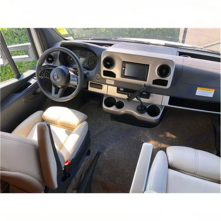 RV rental interior showing the driver's area: modern dashboard, steering wheel, and light-colored captain's chairs.. Thor Motor Coach Chateau 2020