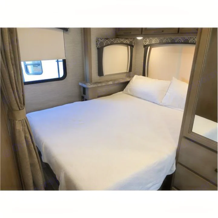 Clean RV rental bedroom featuring a neatly made bed, side windows, and integrated storage/wardrobe.. Thor Motor Coach Chateau 2020