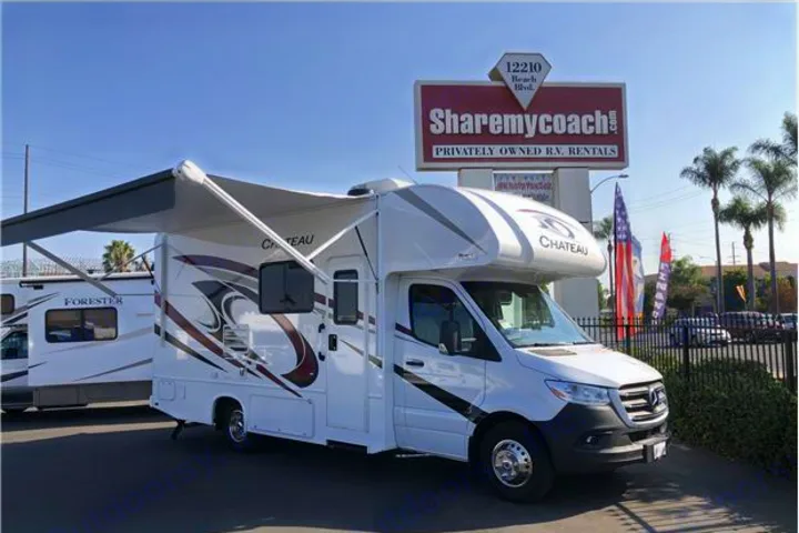 A white Chateau motorhome with its awning extended, parked on a sunlit RV rental lot with a "Sharemycoach.com" sign.. Thor Motor Coach Chateau 2020