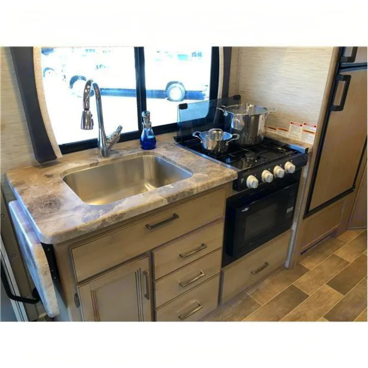 This RV rental features a compact kitchen with a sink, modern faucet, 4-burner stovetop, and microwave.. Thor Motor Coach Chateau 2020
