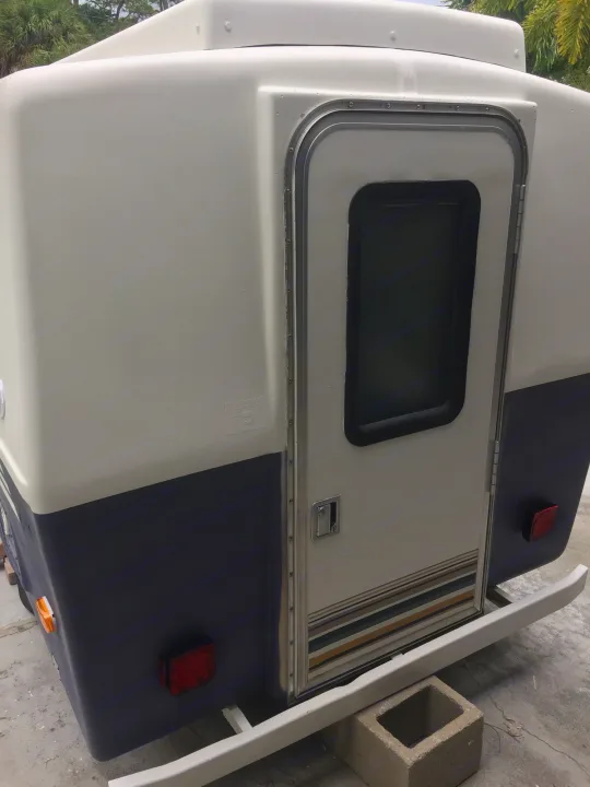Compact two-tone camper, ideal for an rv rental, showing its rear door, window, lights, and bumper.. Hunter Compact Junior 1971