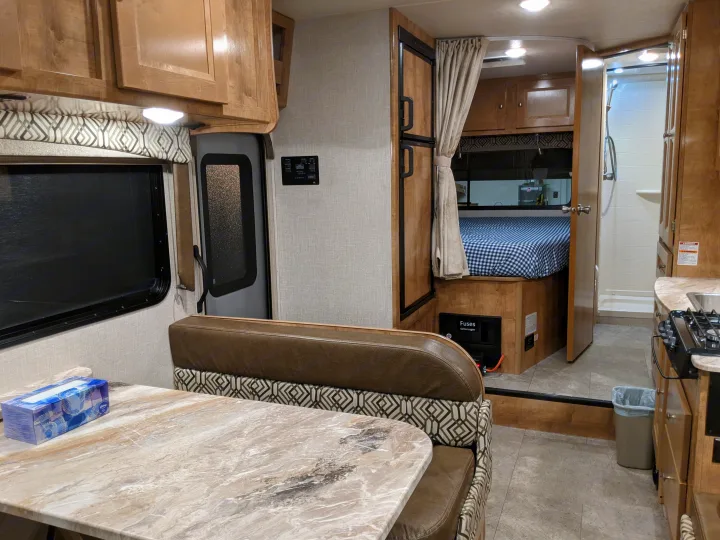Bright RV rental interior with a cozy dinette, well-equipped kitchen, and private rear bedroom & bathroom. Ready for your trip!. Leprechaun 230RB 2020