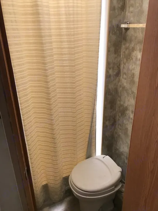 Inside an **rv rental**, showing a beige window shade, bright light, and white toilet in the compact bathroom space.. Winnebago Access 2007