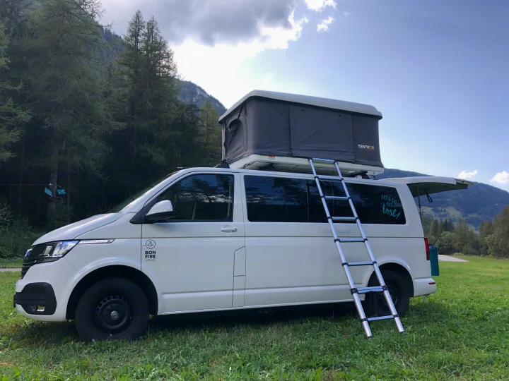White camper van with a TENTBOX rooftop tent and ladder, ready for an RV rental camping adventure in the mountains.. Volkswagen Camper 2019