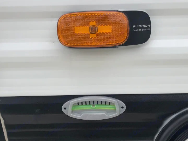 A Furrion camera bracket and amber side marker light are seen above a bubble level on an RV rental, essential for setup.. Keystone RV Hideout 2021