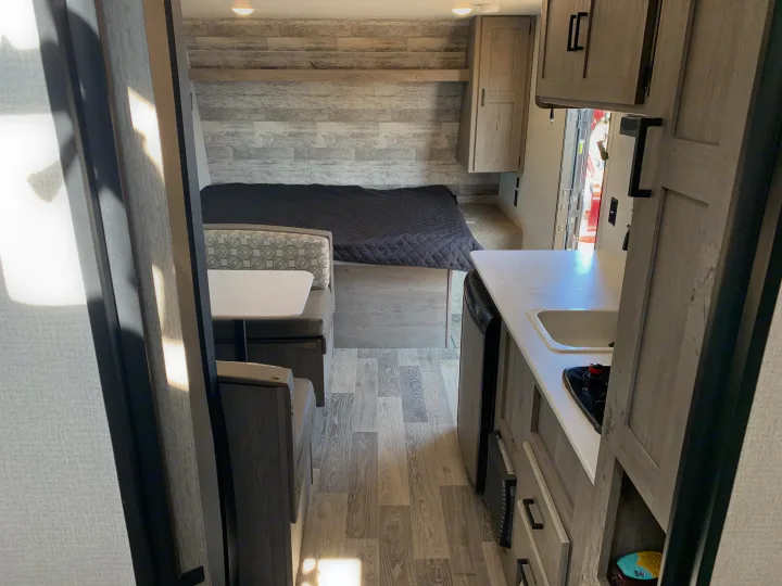 RV rental interior: View of the compact living space with kitchen, dinette, and bed area towards the back.. Keystone Springdale 2021