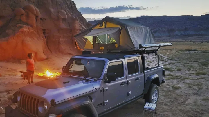 Camping in the desert: A Jeep Gladiator with rooftop tent, campfire, and child. Book your RV rental adventure!. Jeep Gladiator 2020