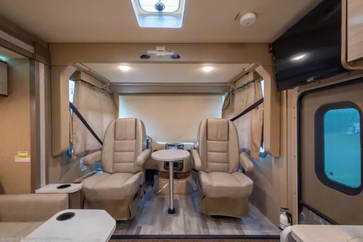 Step inside this RV rental's comfortable cabin featuring swiveling captain's chairs, a removable table, and overhead entertainment for travelers.. Thor Motor Coach Vegas 2020