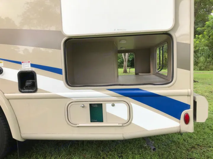 RV rental side view with open pass-through storage, fuel port, and Onan generator. Great for gear!. Thor Motor Coach Vegas 2020