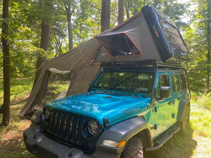Teal Jeep Wrangler with Roofnest rooftop tent and ground annex, set up for camping in a sunny forest. An RV rental alternative!. Other Other 2020