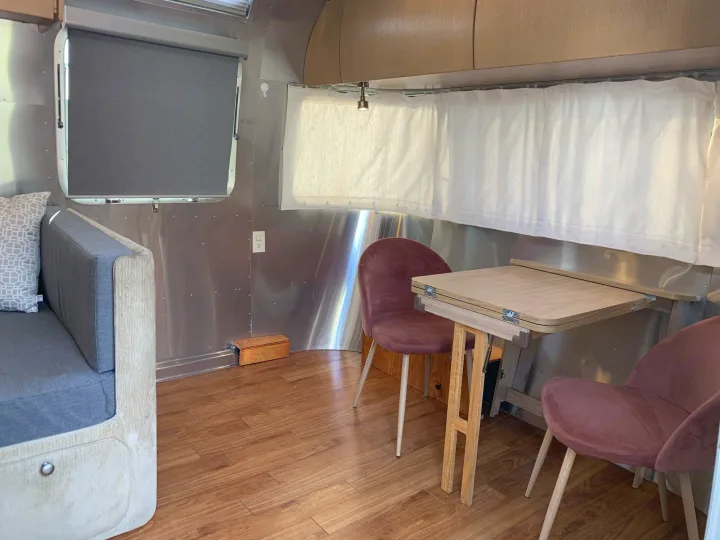 RV rental interior: A modern Airstream living and dining space with a sofa, foldable table, and velvet chairs.. Airstream Safari 2006