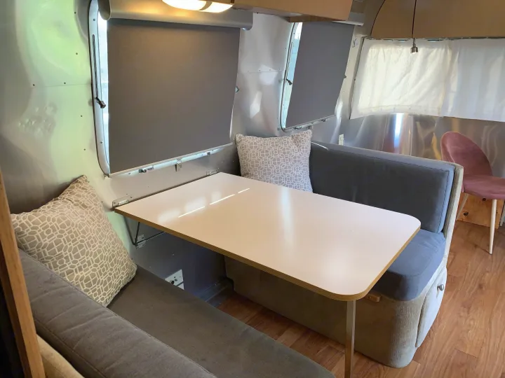 RV rental: Inside a sleek Airstream, a dining booth with a light table, gray cushions, & silver walls.. Airstream Safari 2006