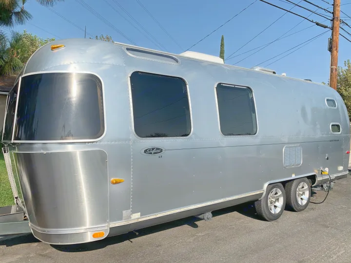 Sleek silver Airstream Safari Edition travel trailer, perfect for your next rv rental adventure, parked outdoors on a sunny day.. Airstream Safari 2006