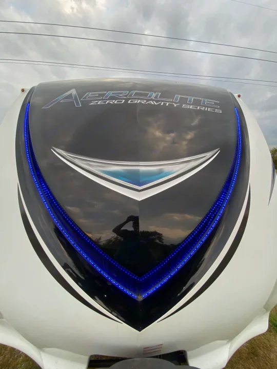 Front of a white and black Aerolite Zero Gravity Series RV rental, illuminated by sleek blue LED lights, ready for camping adventures.. Dutchmen Aerolite 2017